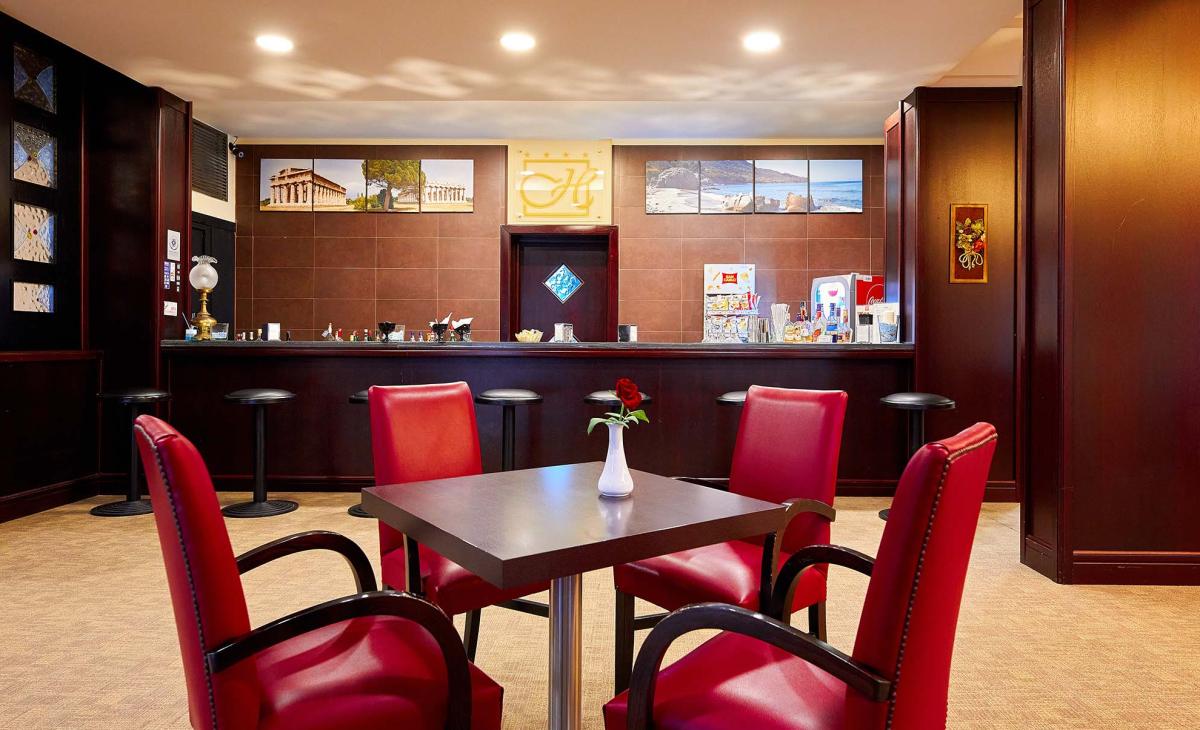 Elegante bar con sedie rosse e decorazioni classiche, atmosfera accogliente e raffinata.