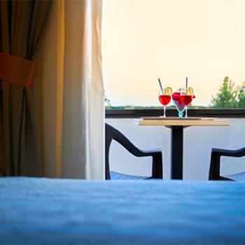 Due bicchieri di cocktail sul tavolo di un balcone al tramonto.