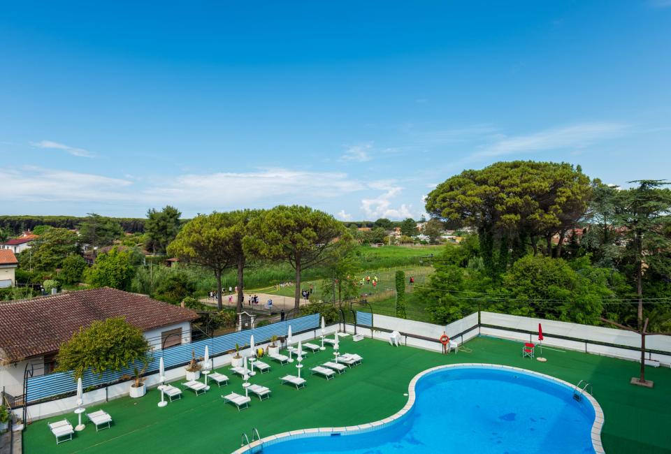 Blue pool surrounded by greenery, clear sky, atmosphere of relaxation and nature.