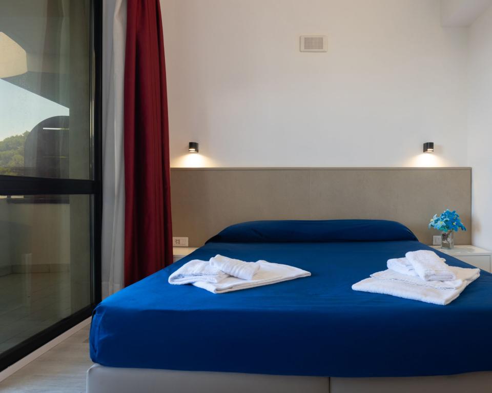 Camera luminosa con letto blu e fiori, atmosfera serena e accogliente.